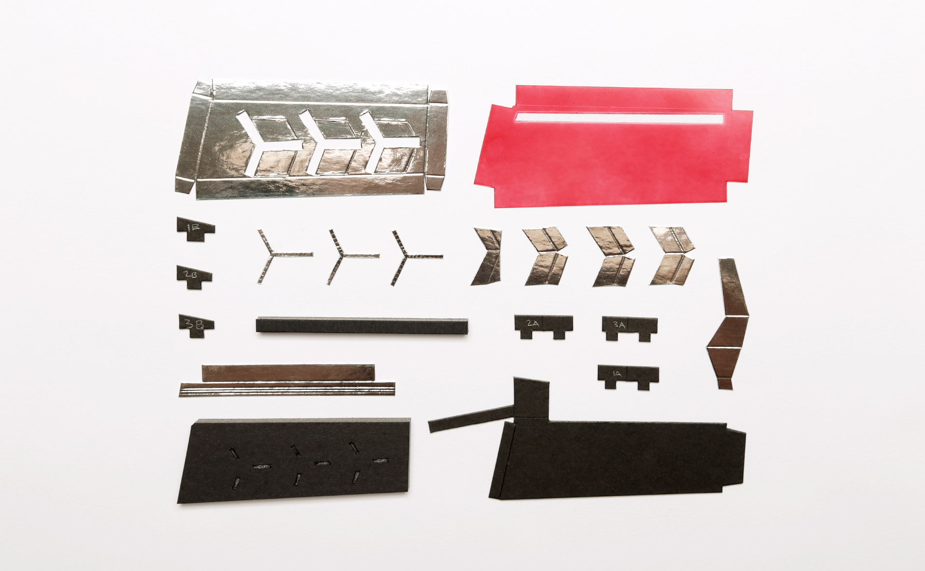 Parts for one tail light- all hand cut from various craft boards. The red tail light lens is clear acetate plastic (same as I used for the car windows) sprayed with Tamiya clear red.